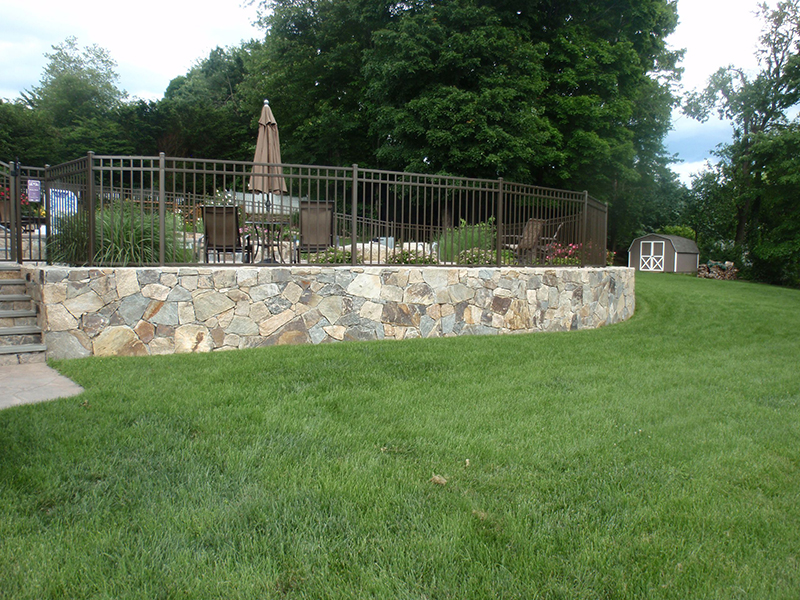 Residential masonry project incorporating stone walls and hardscape structure